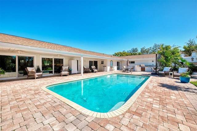 view of pool with a patio, outdoor dry bar, and an outdoor kitchen