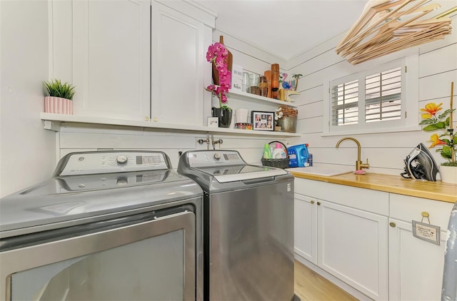 laundry area featuring a sink, cabinet space, light wood-type flooring, and separate washer and dryer