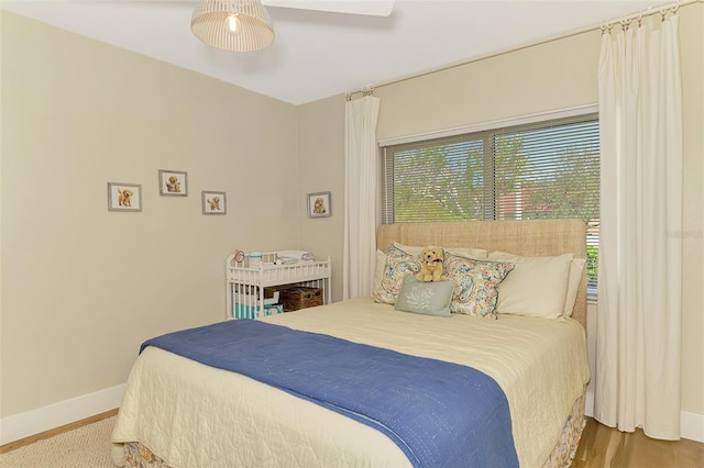 bedroom with a ceiling fan, wood finished floors, and baseboards