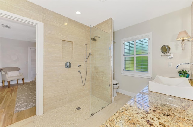 bathroom featuring vanity, visible vents, baseboards, a walk in shower, and toilet