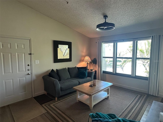 living room featuring baseboards, a textured ceiling, wood finished floors, and vaulted ceiling