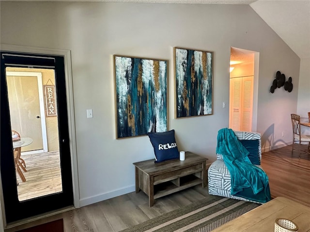 sitting room with baseboards, lofted ceiling, and wood finished floors