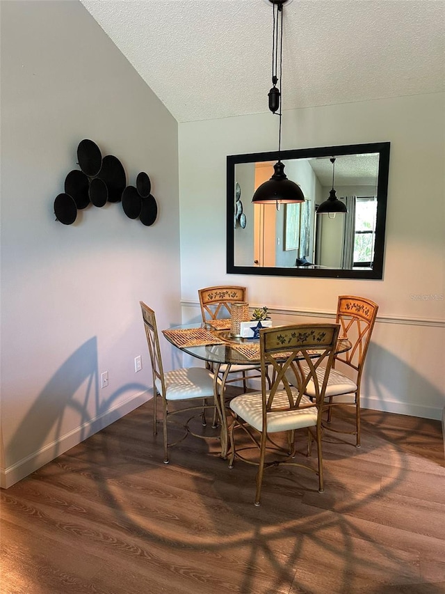 dining space featuring a textured ceiling, baseboards, and wood finished floors