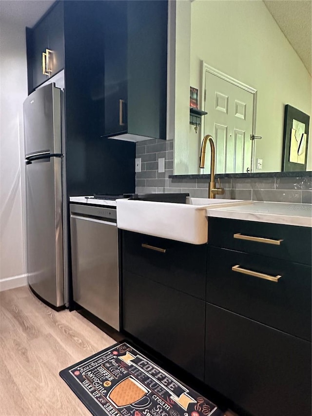 kitchen featuring modern cabinets, a sink, backsplash, stainless steel appliances, and dark cabinets