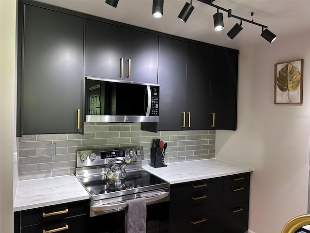 kitchen with light stone counters, stainless steel appliances, dark cabinets, and decorative backsplash