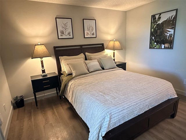 bedroom with wood finished floors, baseboards, and a textured ceiling