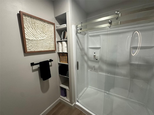 bathroom with a stall shower, baseboards, and wood finished floors