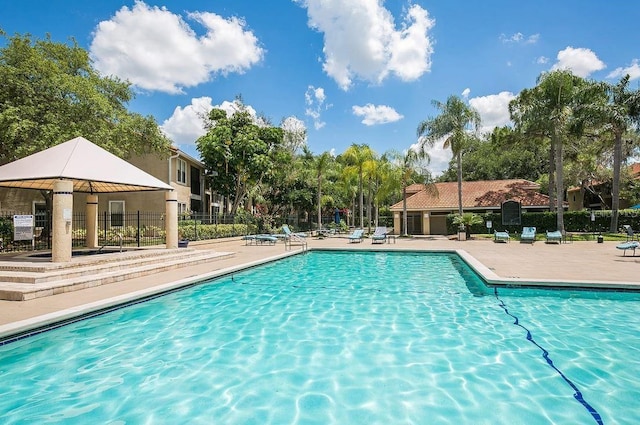 pool with a patio area and fence