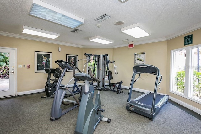 workout area with visible vents, a textured ceiling, crown molding, and baseboards