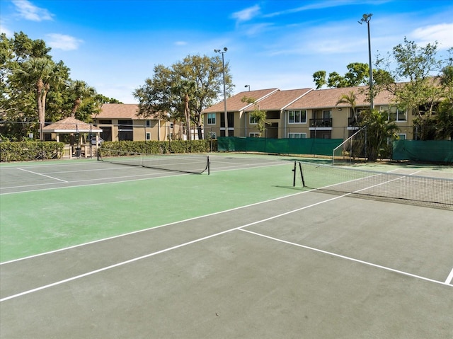 view of tennis court with community basketball court and fence