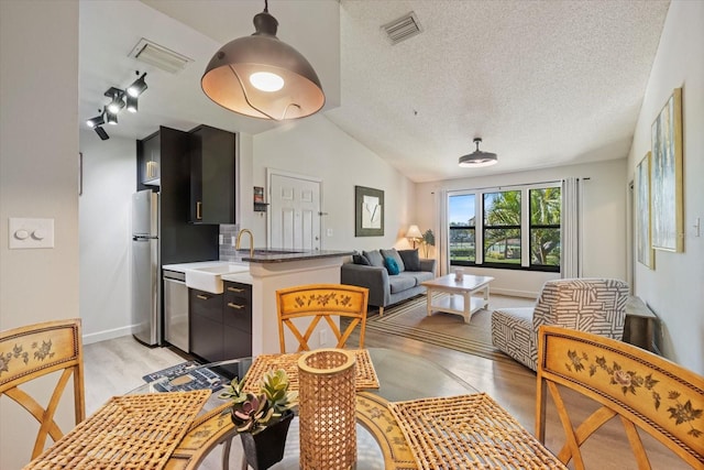 kitchen with a sink, stainless steel appliances, visible vents, and dark cabinetry