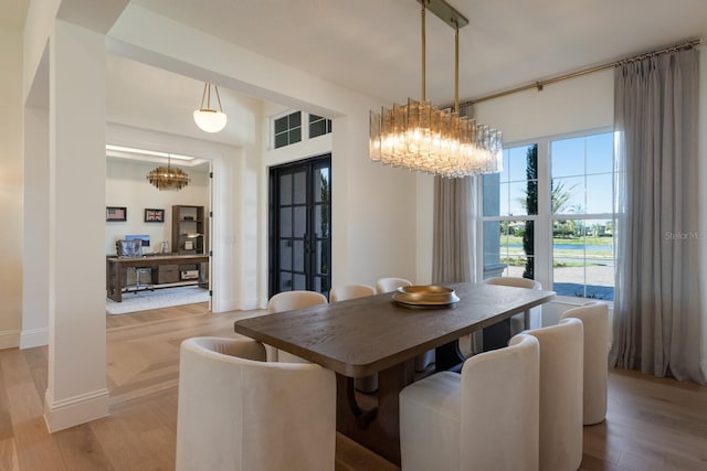 dining room featuring an inviting chandelier, light wood-style floors, baseboards, and french doors