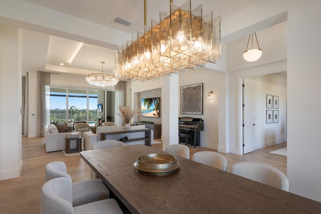 dining space featuring visible vents, baseboards, a chandelier, and light wood-style flooring