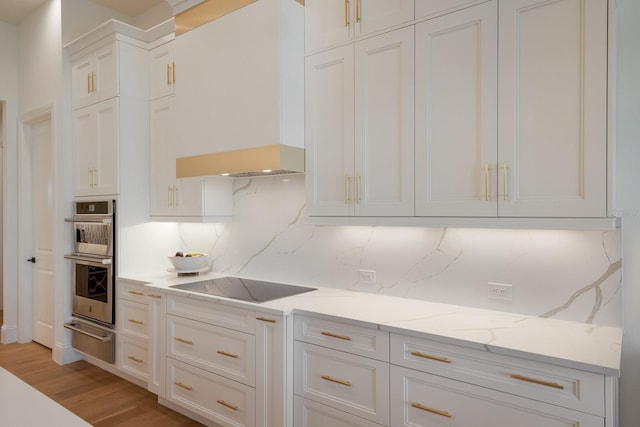 kitchen with black electric stovetop, custom range hood, stainless steel double oven, white cabinetry, and a warming drawer