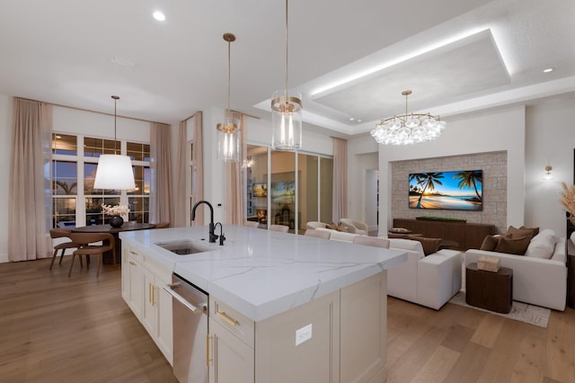 kitchen with open floor plan, stainless steel dishwasher, a raised ceiling, and a sink