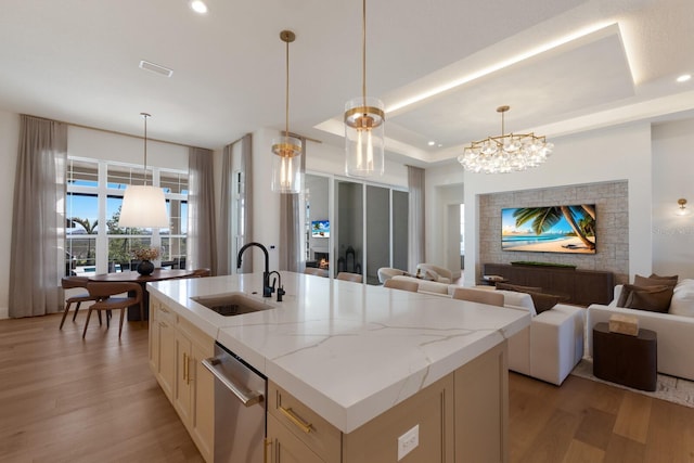 kitchen with visible vents, light wood-style flooring, a sink, open floor plan, and a raised ceiling