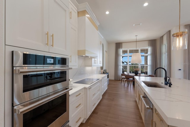 kitchen featuring a sink, stainless steel appliances, white cabinets, and hanging light fixtures