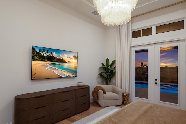 bedroom featuring visible vents, french doors, wood finished floors, a notable chandelier, and access to outside