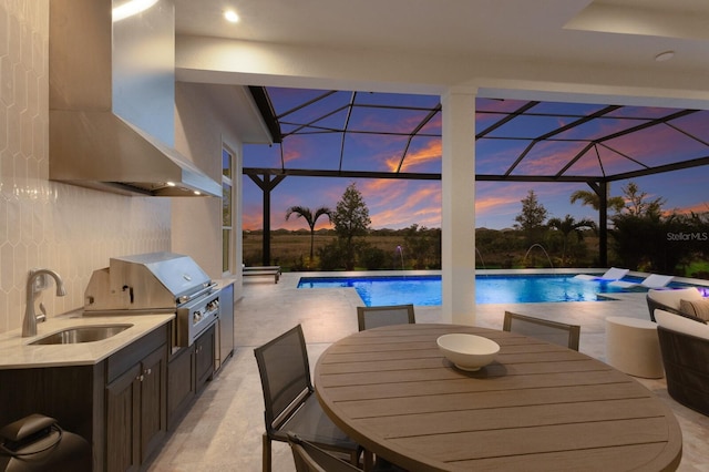 pool with an outdoor kitchen, a sink, a lanai, a patio area, and a grill