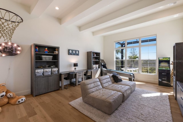 living area with beam ceiling, baseboards, and light wood-type flooring