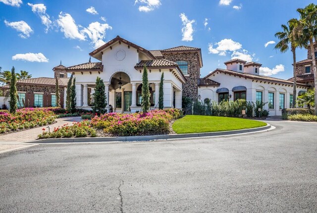 view of front of home featuring stucco siding, a tile roof, and a front lawn