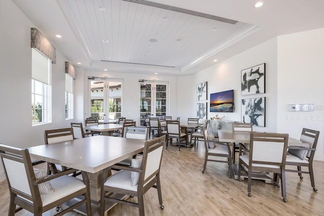 dining area with wood ceiling, light wood-type flooring, and a tray ceiling