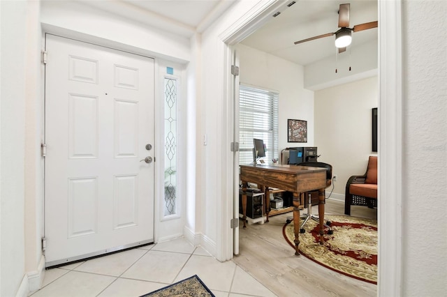 entryway featuring light tile patterned floors, baseboards, and a ceiling fan