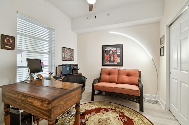 office space with baseboards, light wood-style flooring, and a ceiling fan