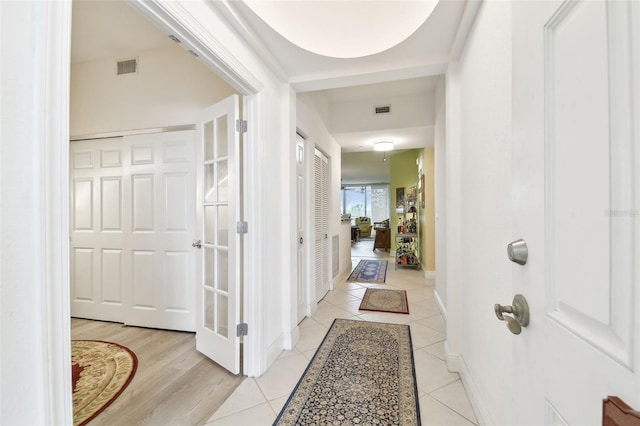 corridor featuring light tile patterned floors, baseboards, and visible vents