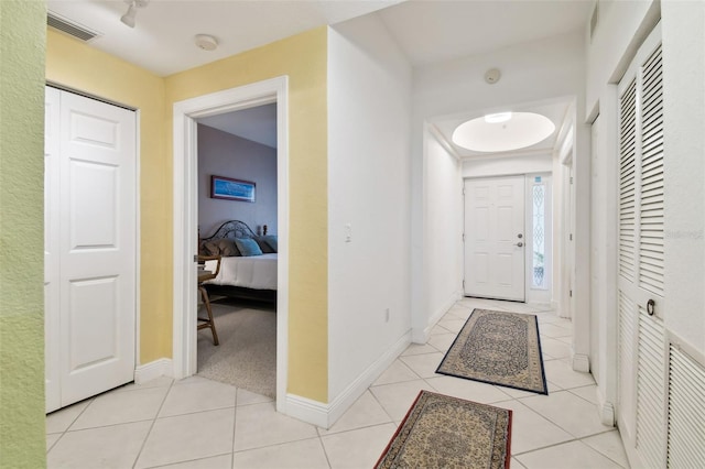 foyer entrance featuring light tile patterned flooring, visible vents, and baseboards