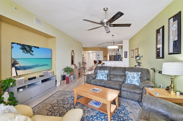 living room with wood finished floors, a ceiling fan, and visible vents