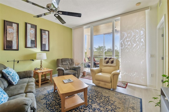 living room featuring ceiling fan, wood finished floors, baseboards, and expansive windows