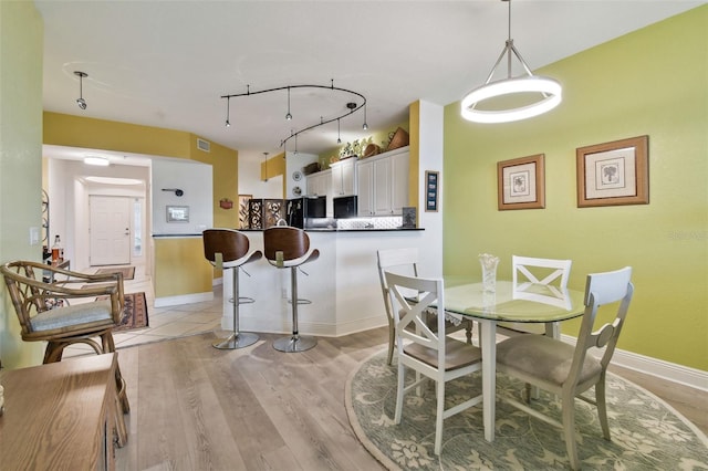 dining space with visible vents, baseboards, light wood-style floors, and track lighting