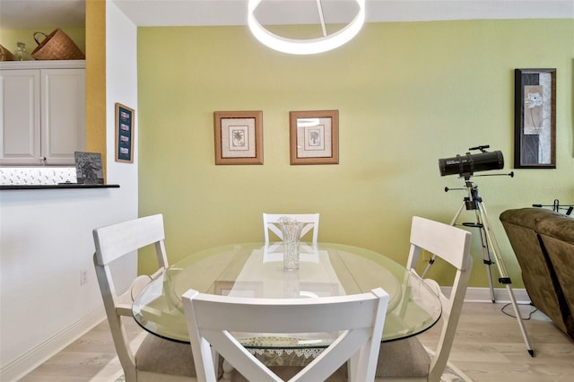 dining space featuring light wood-type flooring and baseboards