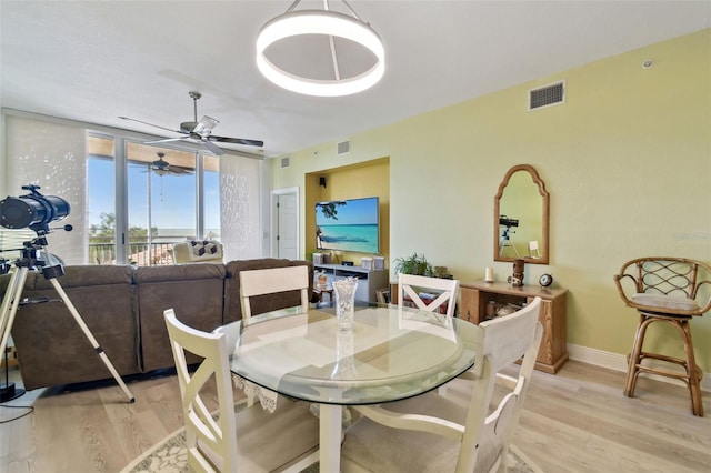 dining space with baseboards, visible vents, and light wood finished floors