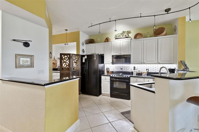 kitchen with black appliances, dark countertops, a peninsula, and a sink