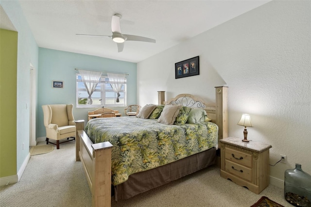 bedroom featuring baseboards, light colored carpet, and a ceiling fan