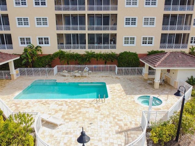 community pool featuring a patio, a community hot tub, and fence