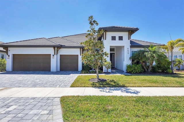 4629 Antrim Dr, Sarasota, FL 34240 - prairie-style house featuring a tile roof, a garage, a front yard, stucco siding, and decorative driveway