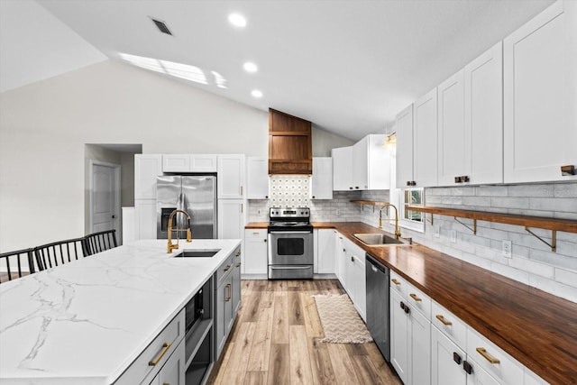 kitchen with a sink, visible vents, appliances with stainless steel finishes, and light wood-style flooring