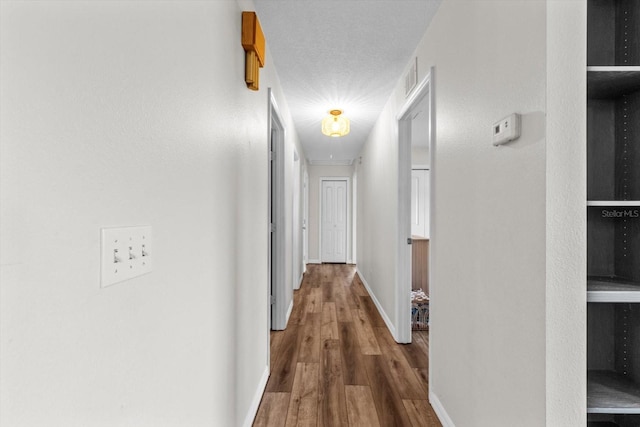 corridor with visible vents, baseboards, and wood finished floors