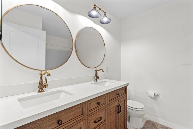 bathroom featuring double vanity, toilet, baseboards, and a sink