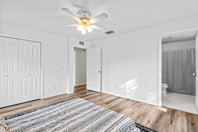 unfurnished bedroom with wood finished floors, visible vents, a closet, and baseboards