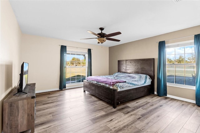 bedroom featuring baseboards, multiple windows, and wood finished floors