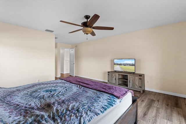 bedroom featuring ceiling fan, wood finished floors, visible vents, and baseboards