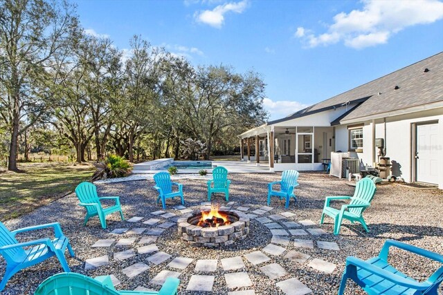 view of patio featuring a fire pit and a sunroom