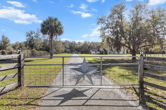 view of gate with a rural view, a yard, and fence