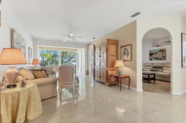 living area with visible vents, baseboards, arched walkways, and a ceiling fan