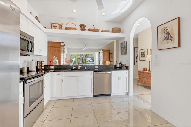 kitchen featuring dark countertops, stainless steel appliances, a ceiling fan, and a sink