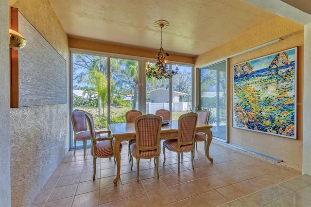 tiled dining room with an inviting chandelier, a textured wall, and a wealth of natural light